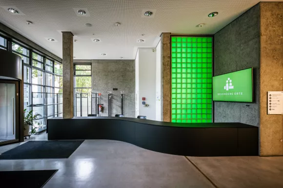 Foyer des Umweltforums mit grüner Belichtung und Logo auf Flat TV