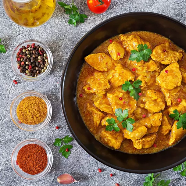 Chicken curry on dark plate with garnishes