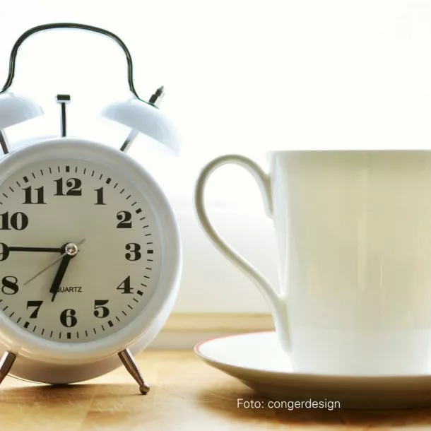 Wecker zeigt morgendliche Uhrzeit und Kaffeetasse
