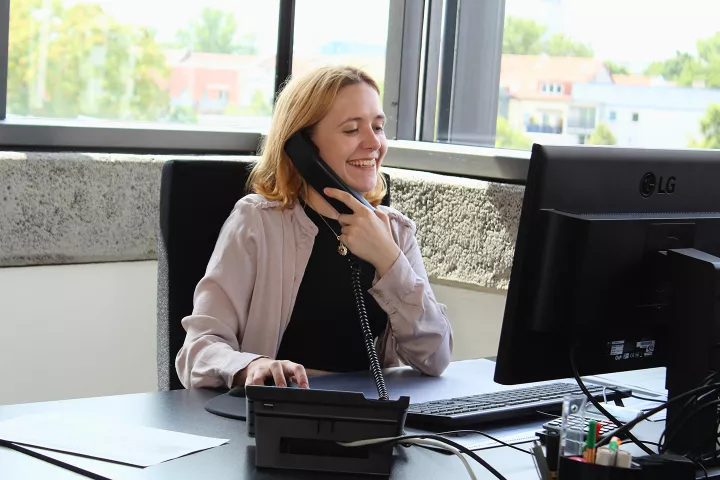 Frau telefoniert mit Kunden an einem Schreibtisch