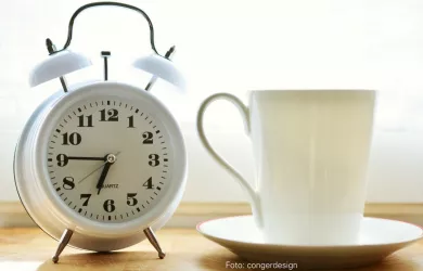 Wecker zeigt morgendliche Uhrzeit und Kaffeetasse