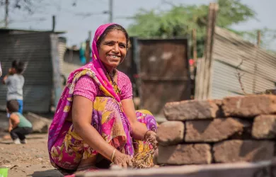 Bunt gekleidete Frau aus Indien sitzt auf dem Boden und lacht