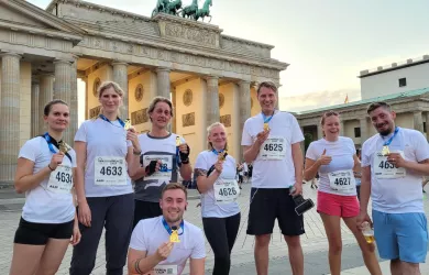 echs Läufer:innen aus dem Team der Besonderen Orte vor dem Brandenburger Tor